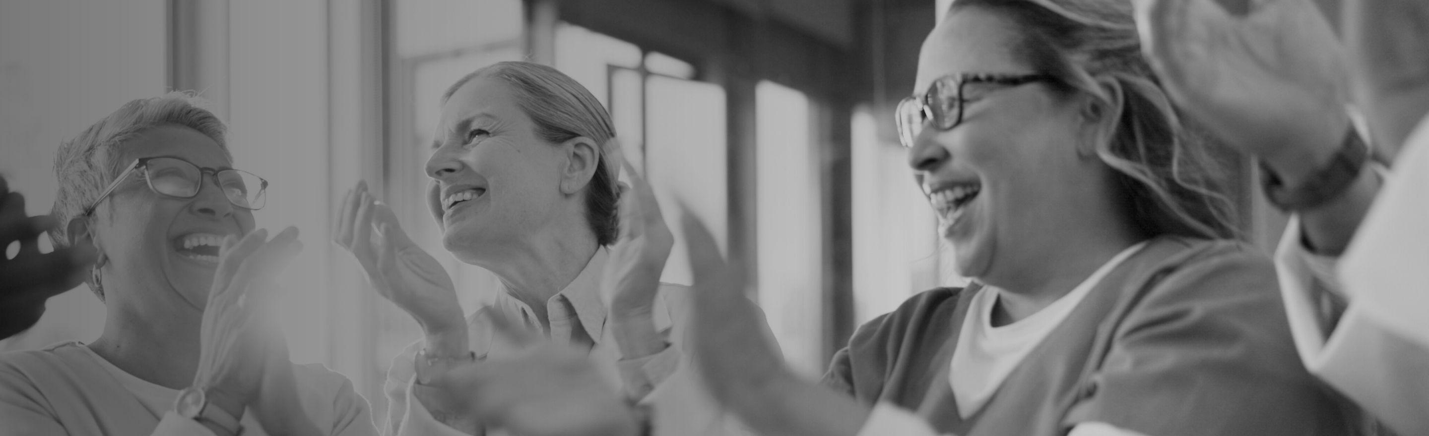 A black and white image of a group of healthcare professionals cheering and clapping