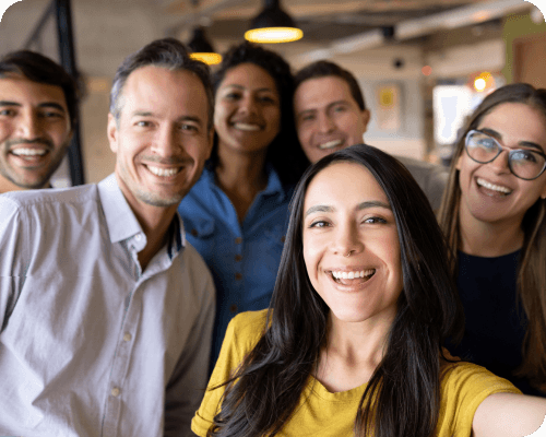 A group of corporate professionals in business casual clothing take a selfie together